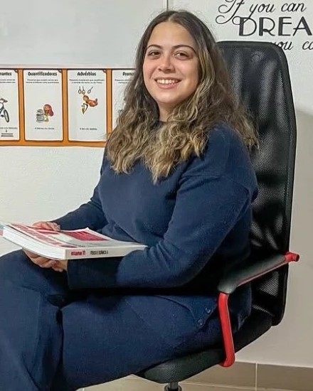 Joana Aparício, sentada numa sala do centro com um manual de Física e Química